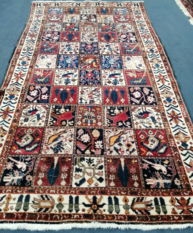 A Persian Garden rug, red, blue and ivory ground with bird and flower motifs, 305 x 169cm